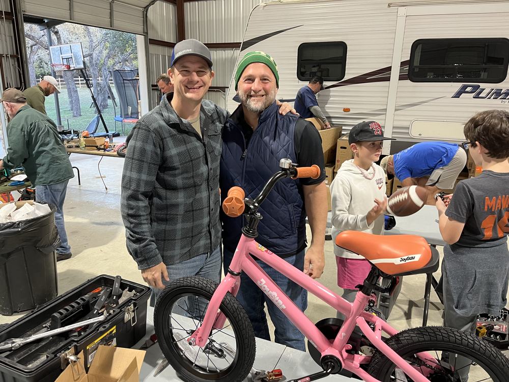 Two builders with a finished pink bike